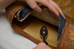 Figure 2. Re-activating adhesive to attach Reemay lining to leather. Photography by V&A Textile Conservation © Victoria and Albert Museum, London