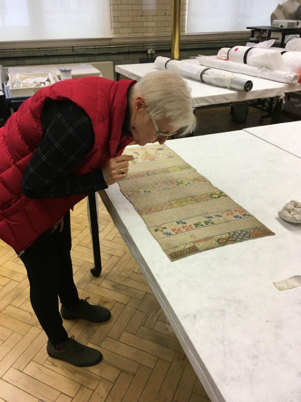 Inez Giles at the Clothworkers' Centre, inspecting an object
