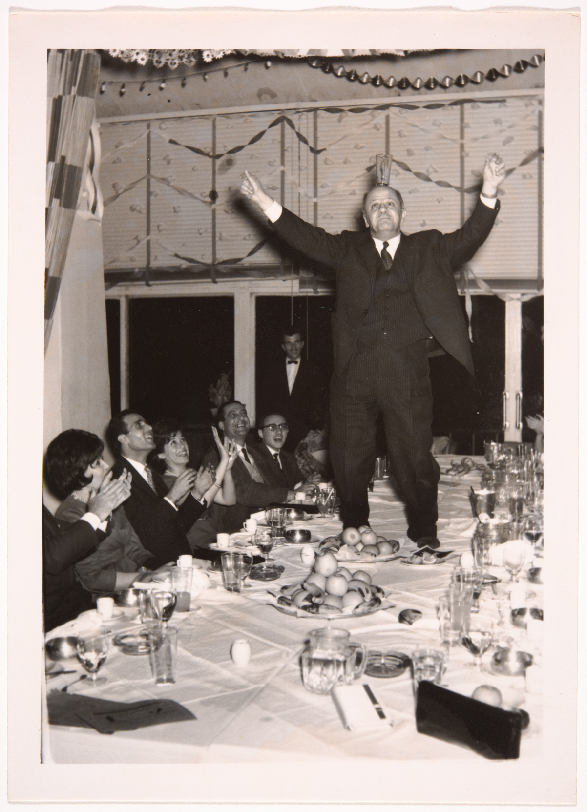 A man standing on a table receiving applause from diners