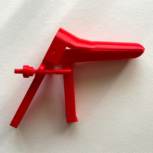 A red 3D printed speculum on its side