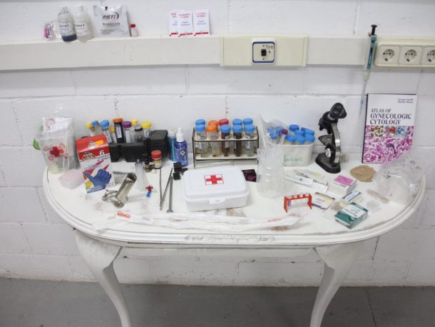 A white table covered with medical equipment, including a first aid box and a microscope