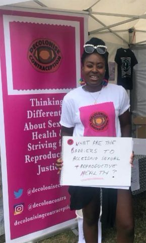A woman stands in front of a poster promoting reproductive health