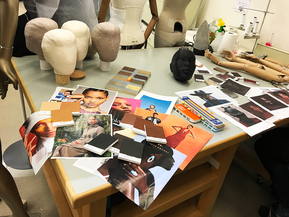 Desk with moodboard images of models, mannequin arms and mannequin heads