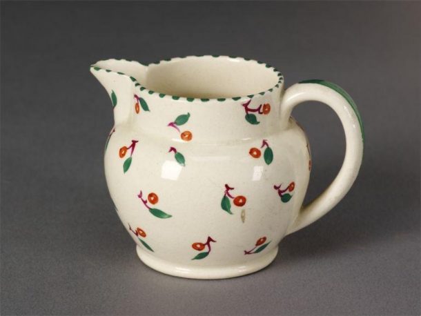 A cream milk jug decorated with cherries