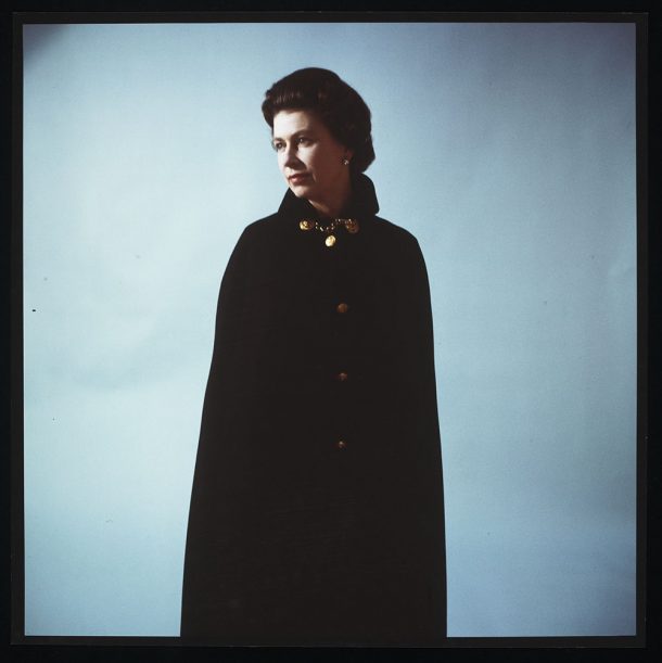 Queen Elizabeth II wearing a black cape against a plain background in 1968