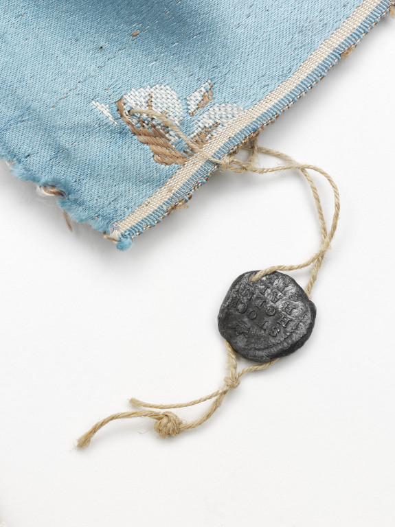 An 1813 lead customs seal attached to the corner of a silk furnishing fabric, woven by Jean Pierre Mazer, Stockholm, 1813.