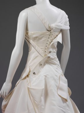 The corset fastenings on the back of the dress's bodice are left exposed