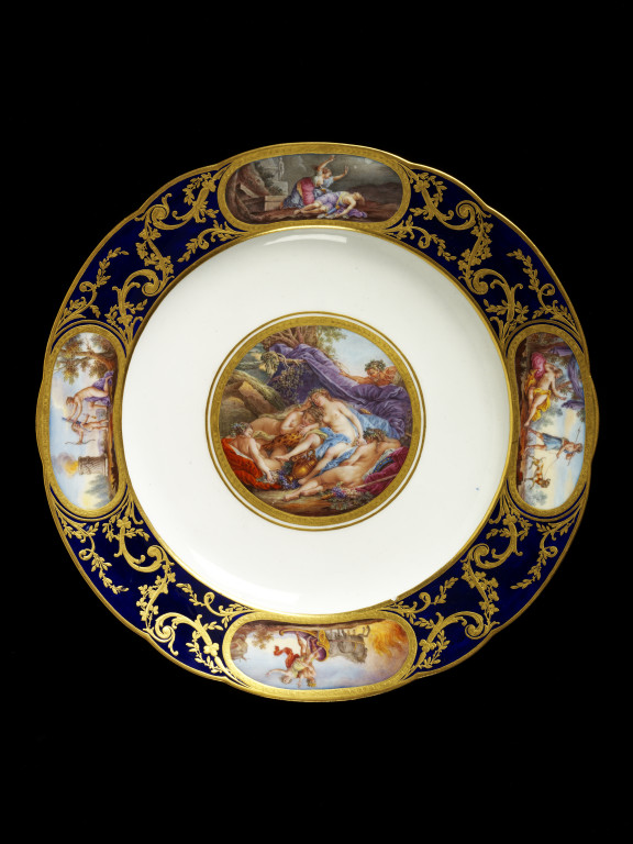 Soft-paste porcelain plate, painted in enamels and gilt,  made by Sèvres porcelain factory, France, about 1785. The central scene 'Les Bacchantes endormies',  was taken from an engraving by Rene Gaillard, after Francois Boucher. V&A C.452-1921