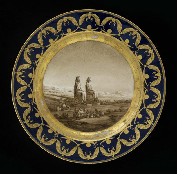 Plate from the 'Egyptian Service', hard-paste porcelain, painted in enamels and gilt, showing the statue of Amenhotep III at Luxor, made at the Sèvres porcelain factory, France, 1810-12. V&A C.124-1979
