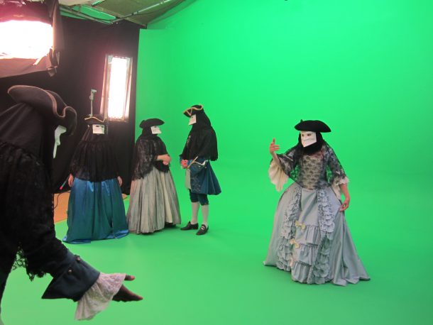 A cast in costume filming in front of a green screen