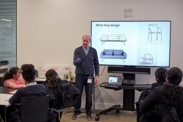 Designer Sam Hecht giving a presentation to a small group in front of a TV