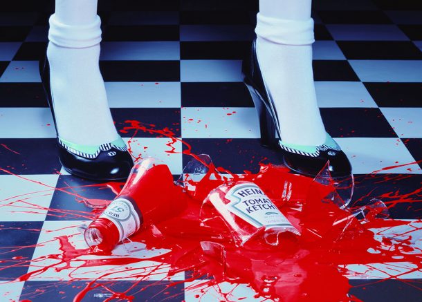 A smashed bottle of ketchup, with a pair of feet in high-heels behind