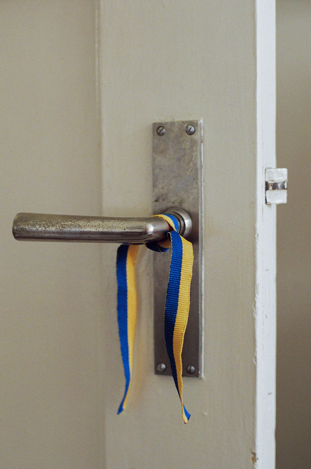 A door handle tied with a ribbon in the colours of the Ukrainian flag