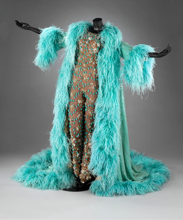 Catsuit with turquoise beads and gold embellishments, with a turquoise feathered evening coat worn over the top