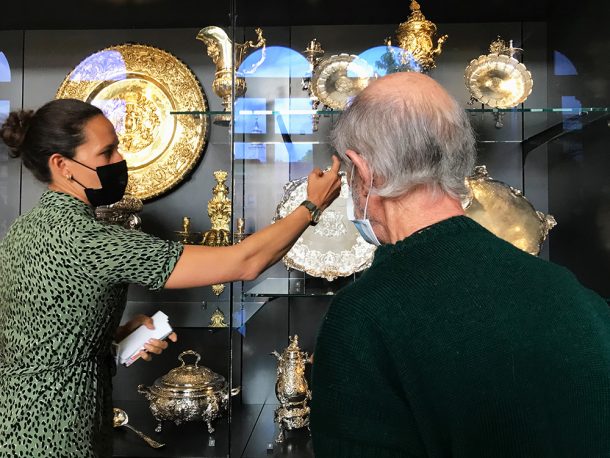 Curator pointing out a silver object in the gallery to  man