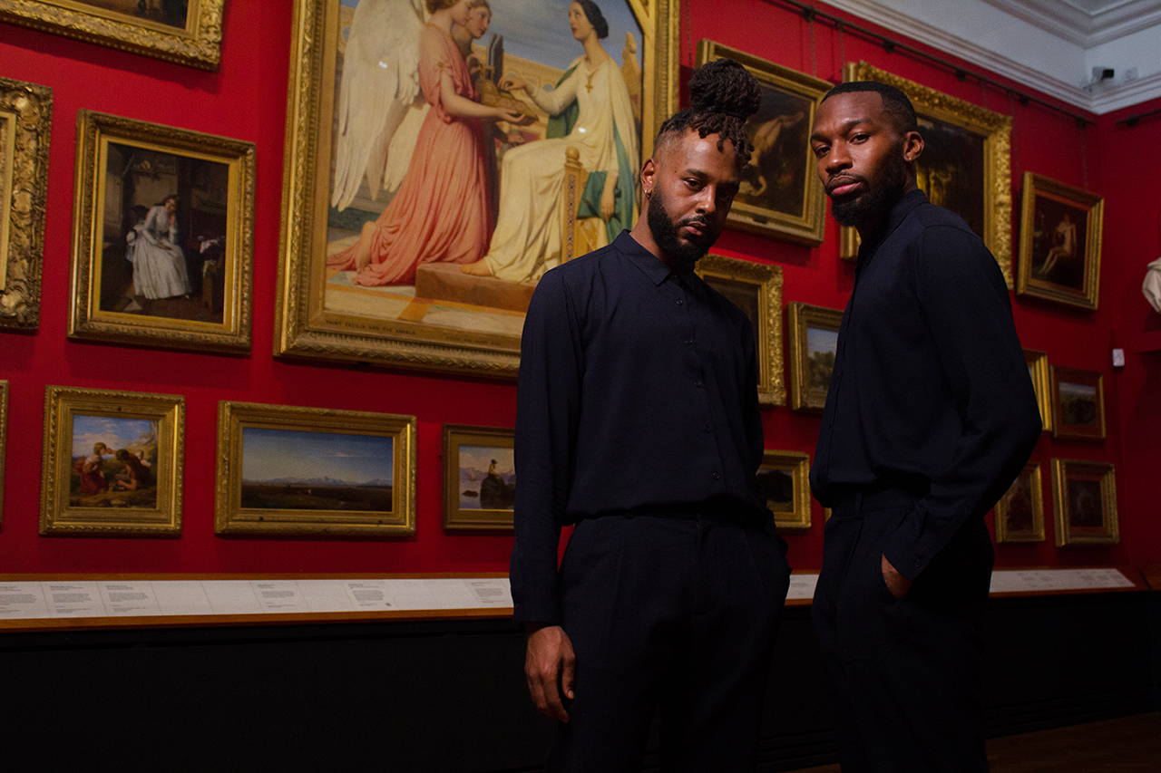 Two dancers stood in a red gallery