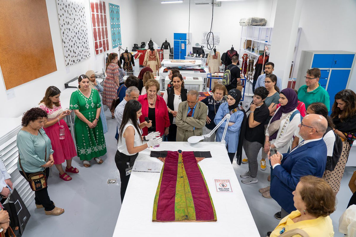 A large group of people looking at a textile in a conservation studio