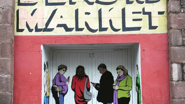 A doorway painted with figures as though they're waiting in a queue. The sign above the doorway read "dens rd market"