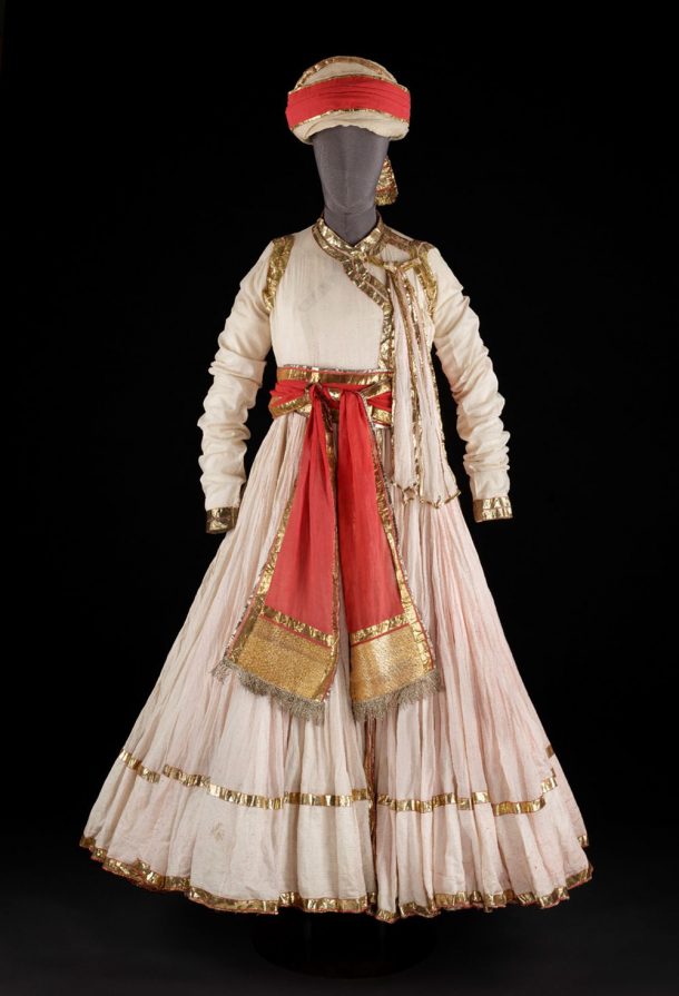 An ornate, white costume tied with a red sash and worn with a matching turban
