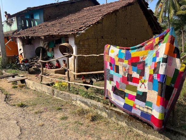 A quilt hung on a fence to dry
