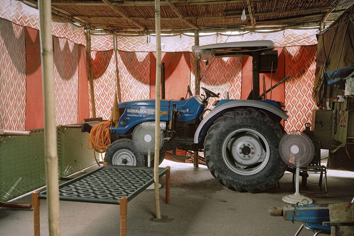 A tractor inside a temporary structure, in front of red canvas