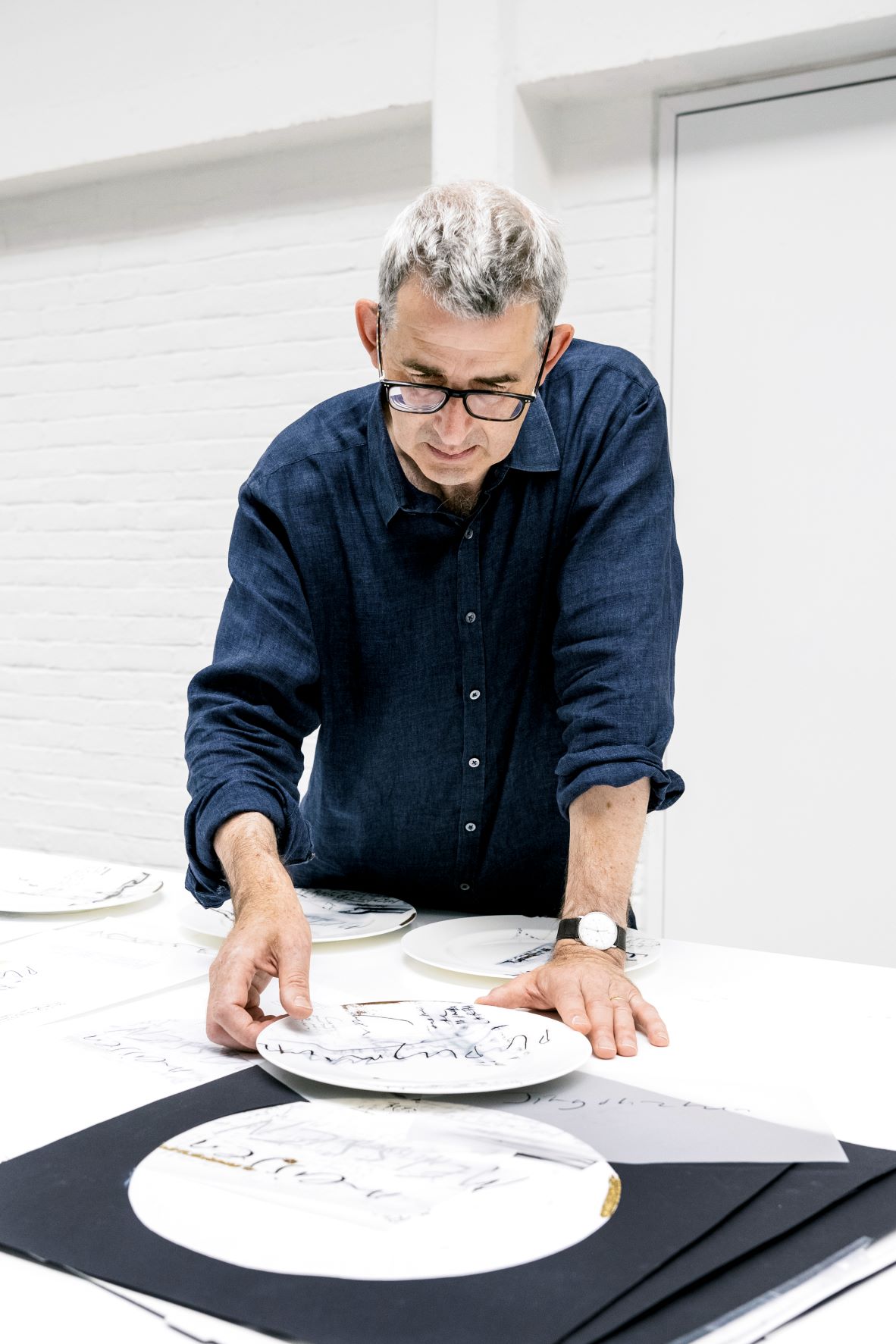 Edmund de Waal examining a plate on a table