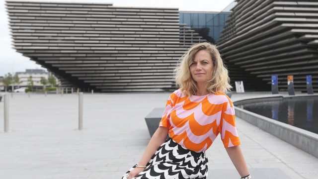 Woman leaning on a bench outside of V&A Dundee