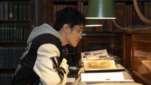 Library user reading at a lamp lit desk