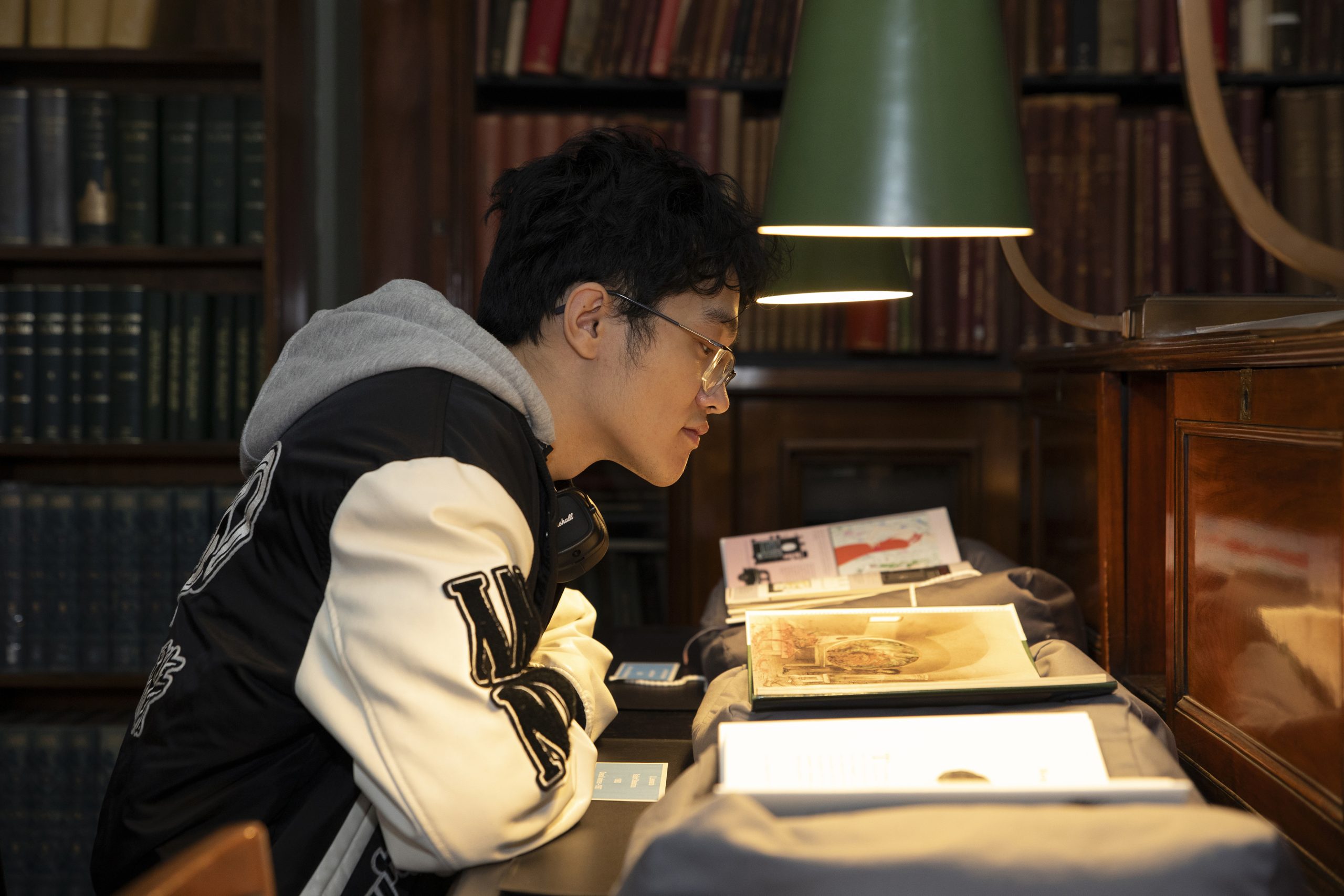 Library user reading at a lamp lit desk