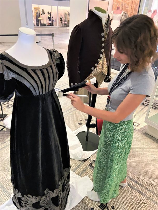 A curator dusting a black silk velvet dress