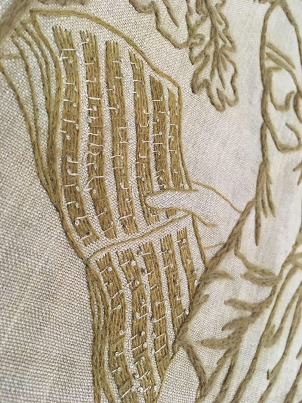 Close up of a hand holding a musical score in various brown wools