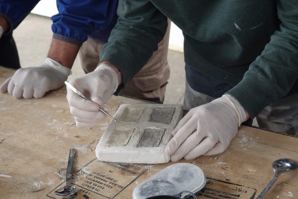 close up of person putting porcelain paste into plaster test tile mould