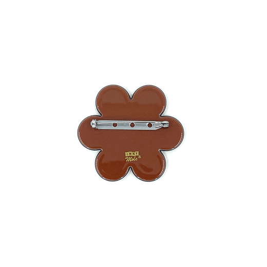 A brick red flower shaped brooch seen from the back, on a white background.