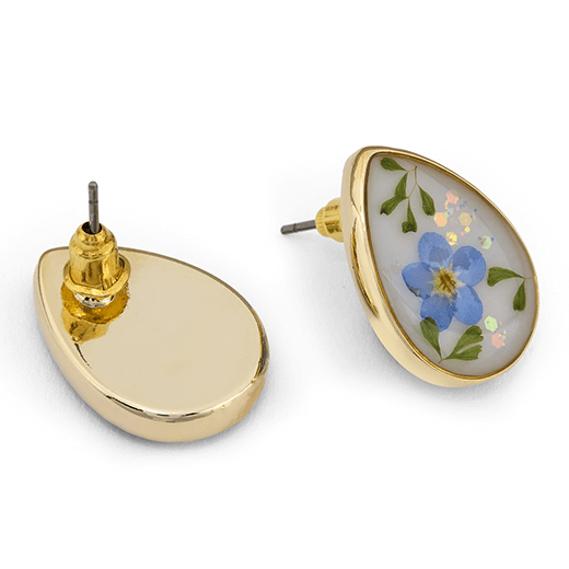 A pair of teardrop shaped earrings with real flowers captured in resin inside a golden frame. One of the earrings is turned to show its back.