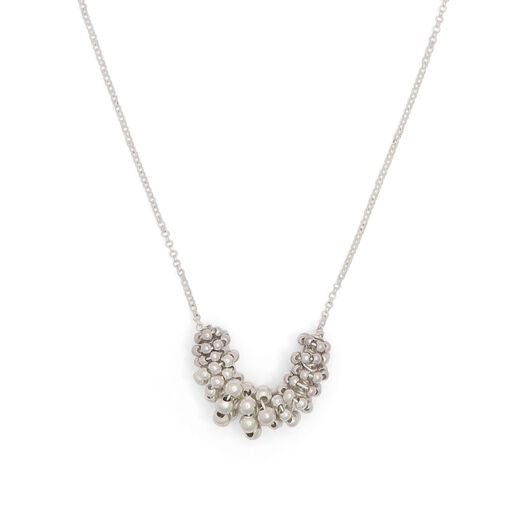 A close up of a silver necklace pendant descending from a delicate chain.