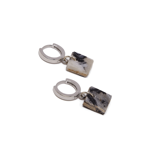 A pair of silver earrings with a black and white square pendant on a white surface.