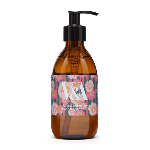 A brown glass bottle with a black pump and a pink label. Printed on the label are a floral pattern and the V&A logo in white.