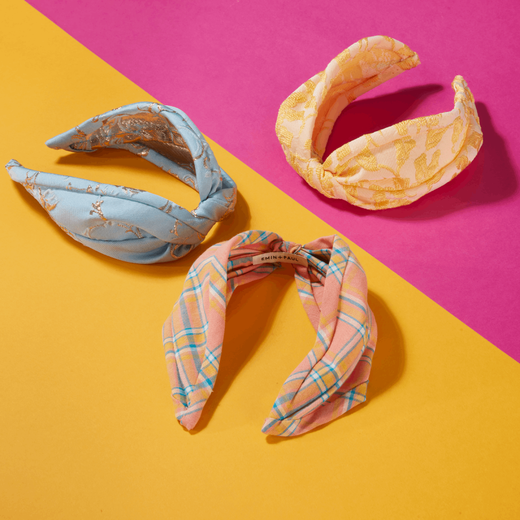 Three fabric headbands are displayed on a yellow and magenta background.