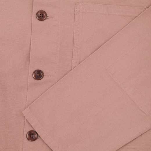 A close up of the front of a dusty pink shirt, showing three brown buttons.