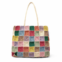 Handwoven raffia tote bag featuring a patchwork of multicoloured squares.