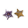 Two star-shaped brooches. One is made of red gleaming stones and glass beads while the other is turned to show the clasp at its back.