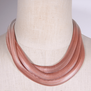 A pink three strand chain necklace placed around a mannequin's neck.