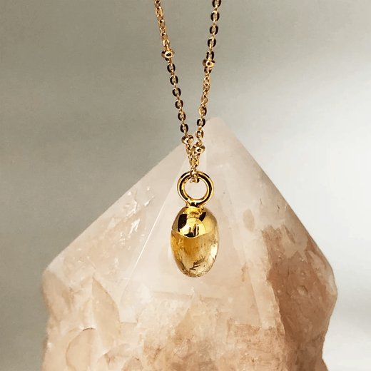 A deep yellow stone pendant on a gold chain.