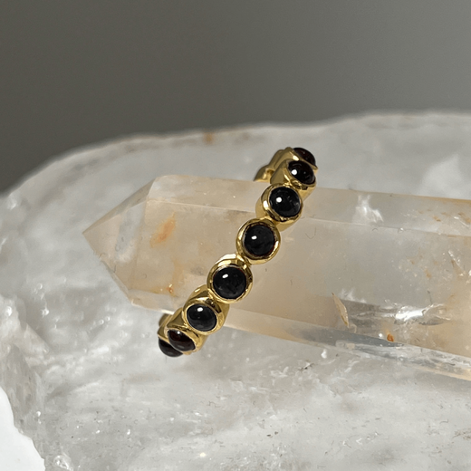 Gold ring with black onyx stones on pink crystals.