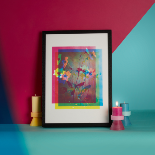 A framed copy of Henry Irving's Single Dahlia print is accompanied by block-colour candles on a bright graphic setting
