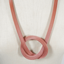 Detail of a knotted silver and pink mesh necklace.