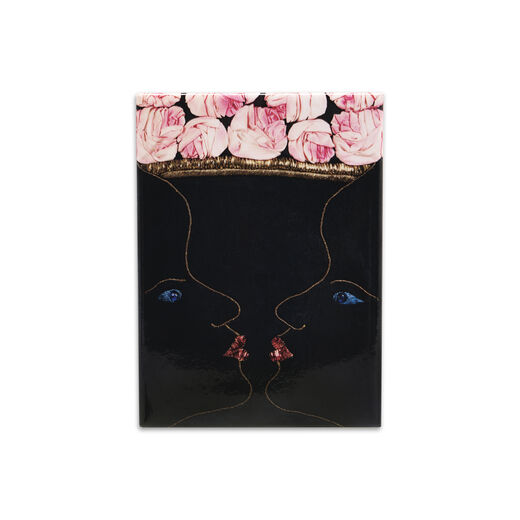 Full magnet featuring two mirrored, kissing faces that form the illusion of a vase of roses adapted from the Schiaparelli evening coat design 
