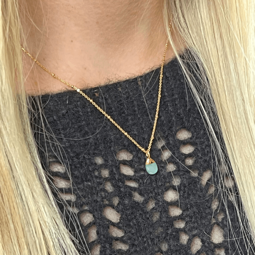 Close up of a blonde woman wearing a pendant gold chain necklace.