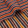 A detail shot of a scarf with a pattern of vertical and horizontal stripes in orange, yellow, blue and white.