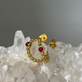 Gold hoop earrings with a central round red stones photographed on clear crystals.